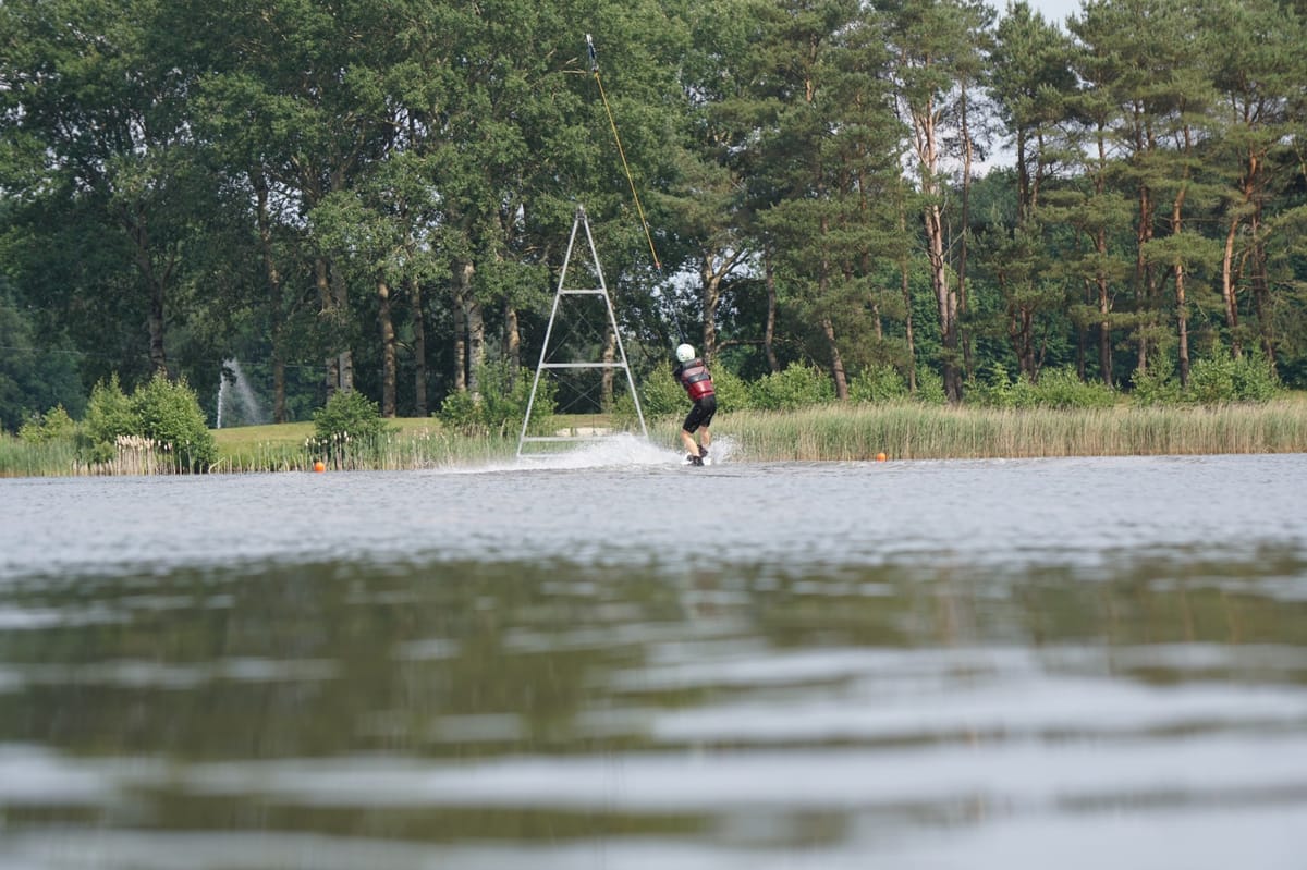Cable wakeboarder riding switch on a straight section of the cable